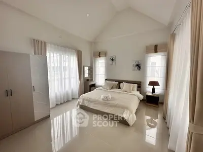 Spacious and bright bedroom with modern decor and large windows.