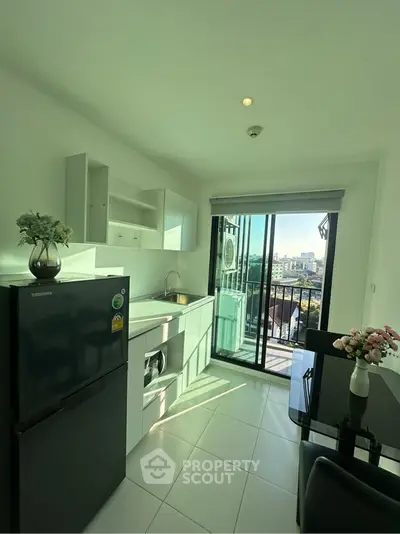 Modern kitchen with balcony view, sleek appliances, and elegant dining area in a bright apartment.