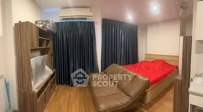 Cozy bedroom with wooden flooring, red bedding, and modern furniture