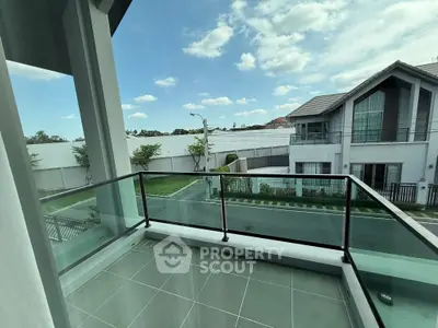 Modern balcony with glass railing offering a serene neighborhood view.
