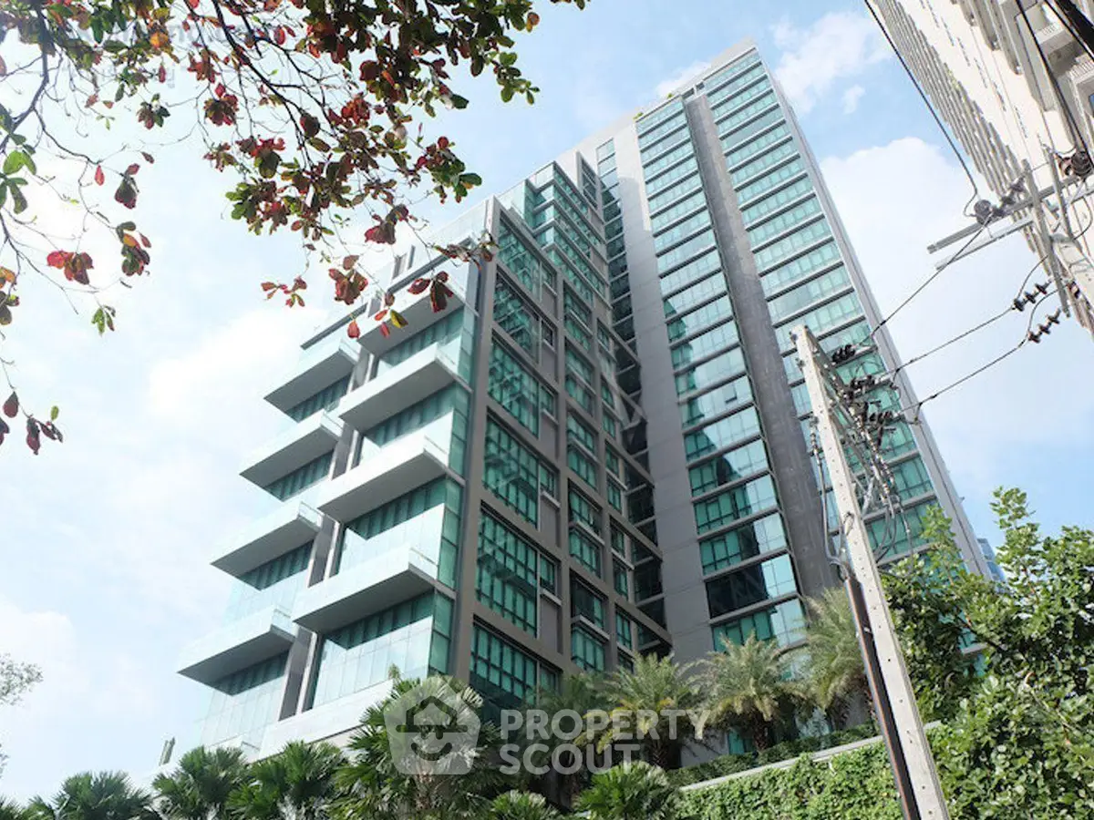 Modern high-rise building with lush greenery and clear blue sky