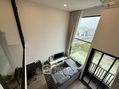 Modern living room with large window offering stunning city view, cozy sofa, and stylish decor.