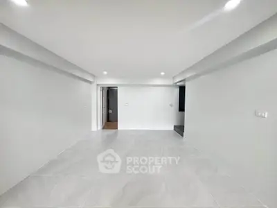 Spacious modern living room with sleek white tiles and recessed lighting.