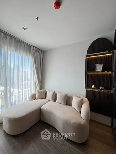 Modern living room with stylish sofa and built-in shelving, featuring large windows with city view.