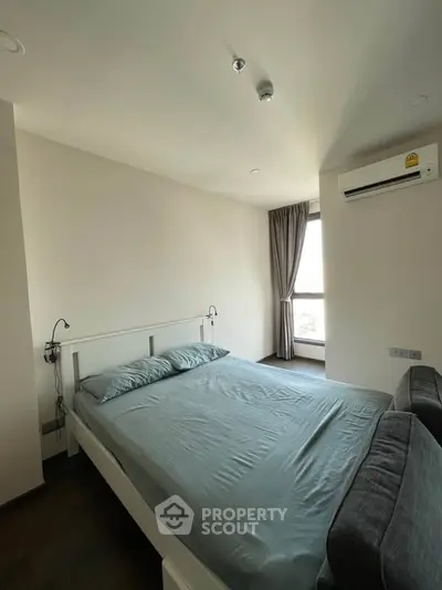 Modern bedroom with natural light and air conditioning in a stylish apartment.