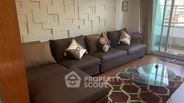 Stylish living room with modern sofa and glass coffee table, opening to a balcony with city view.