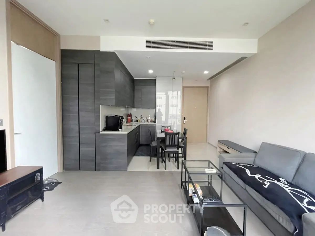 Modern living room with open kitchen, sleek furniture, and stylish decor in a contemporary apartment.