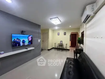 Modern living room with sleek TV setup and dining area, featuring stylish decor and air conditioning.