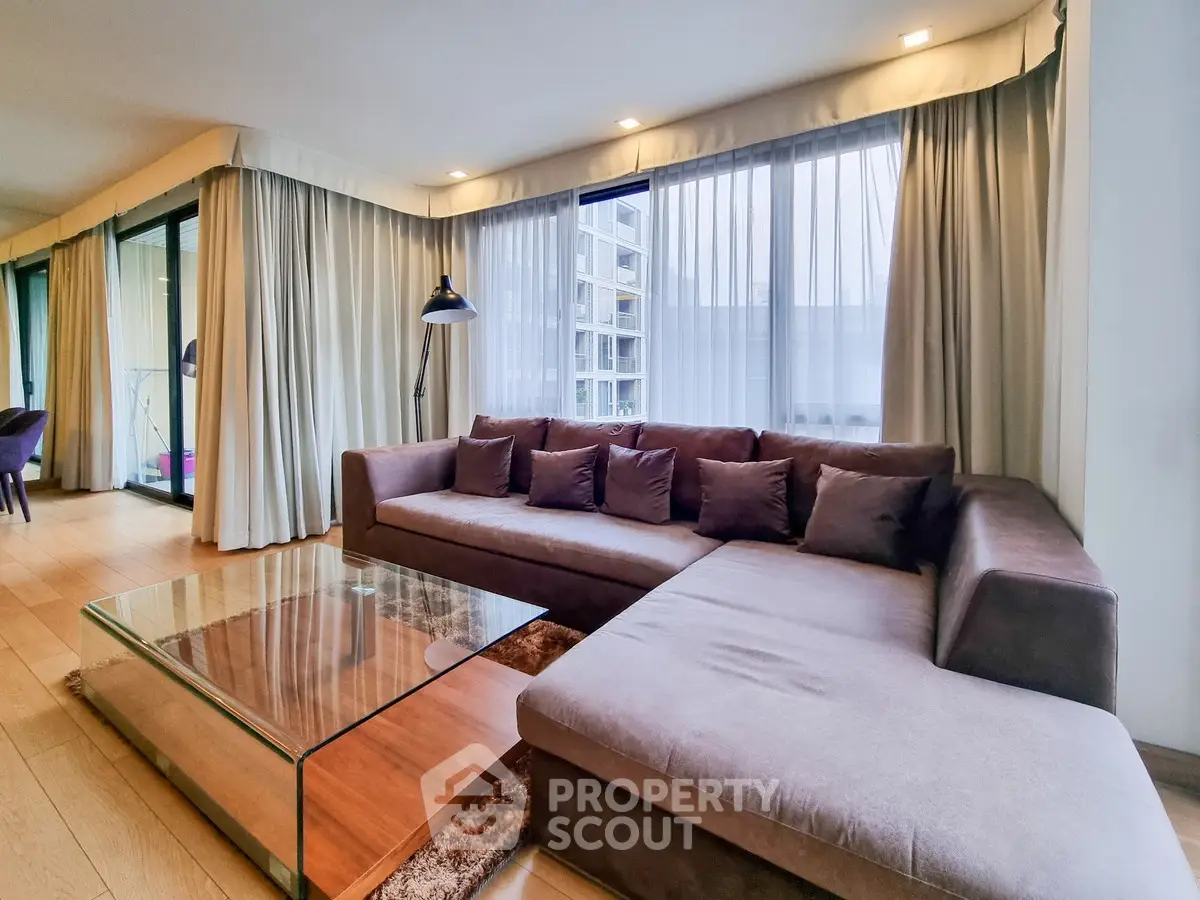 Spacious modern living room with large sectional sofa and floor-to-ceiling windows