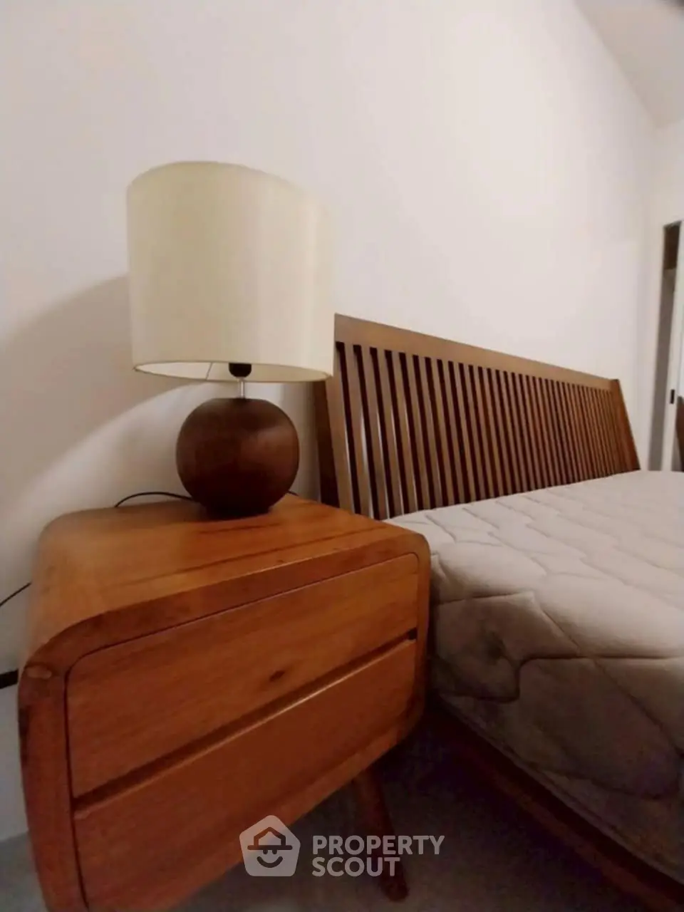 Cozy bedroom with wooden bed frame and matching nightstand, perfect for a serene retreat.