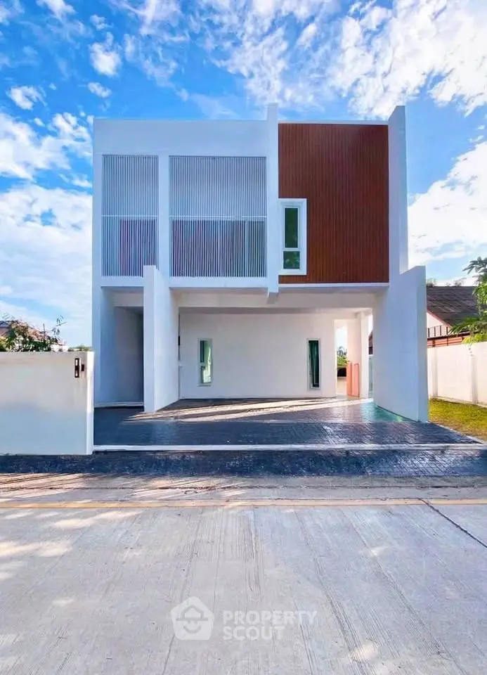 Modern minimalist two-story house with sleek facade and spacious driveway under a clear blue sky.