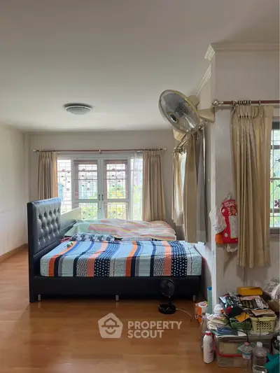 Spacious bedroom with large windows and modern decor, perfect for comfortable living.