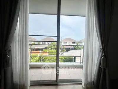 Spacious balcony view with sliding glass doors and elegant curtains in a modern home.