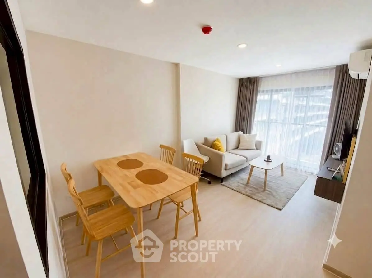 Modern living room with cozy sofa, dining table, and large window for natural light.