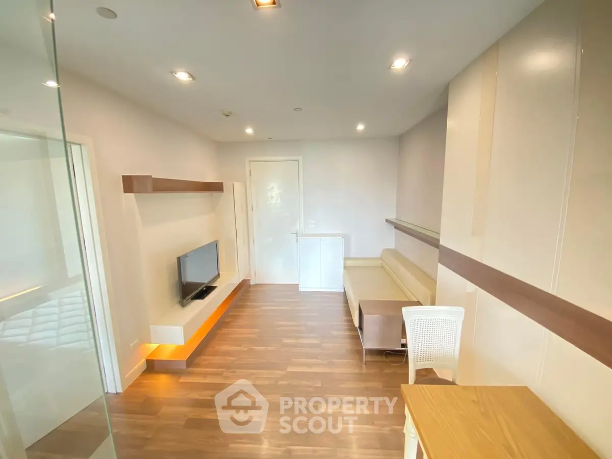 Bright and modern living space with sleek wooden flooring, recessed lighting, and a cozy fireplace, perfect for urban living.