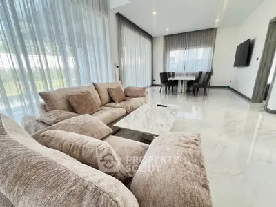 Luxurious modern living room with plush sofas and elegant dining area, featuring floor-to-ceiling windows.