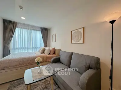 Cozy studio apartment with modern decor, featuring a comfortable bed and stylish sofa in a well-lit space.