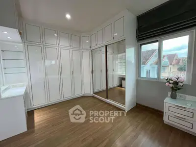 Spacious bedroom with elegant built-in wardrobes and large window view.