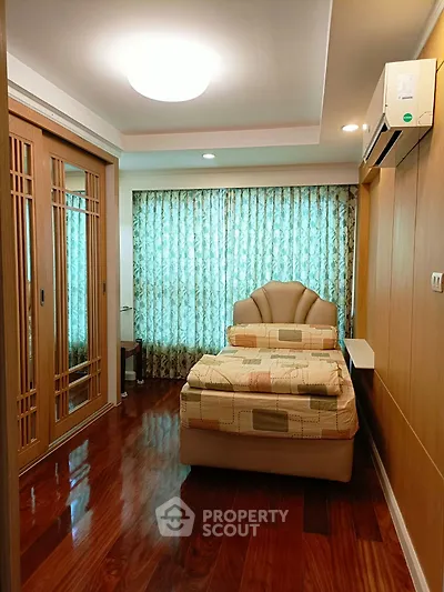 Cozy bedroom with elegant wooden flooring and stylish bed in a well-lit space.