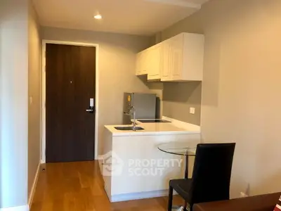 Modern compact kitchen with sleek cabinetry and integrated appliances in cozy apartment.