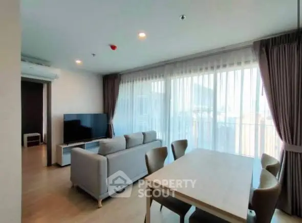 Spacious modern living room with large windows and dining area, perfect for urban living.