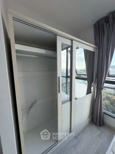 Spacious bedroom with large mirrored wardrobe and scenic window view