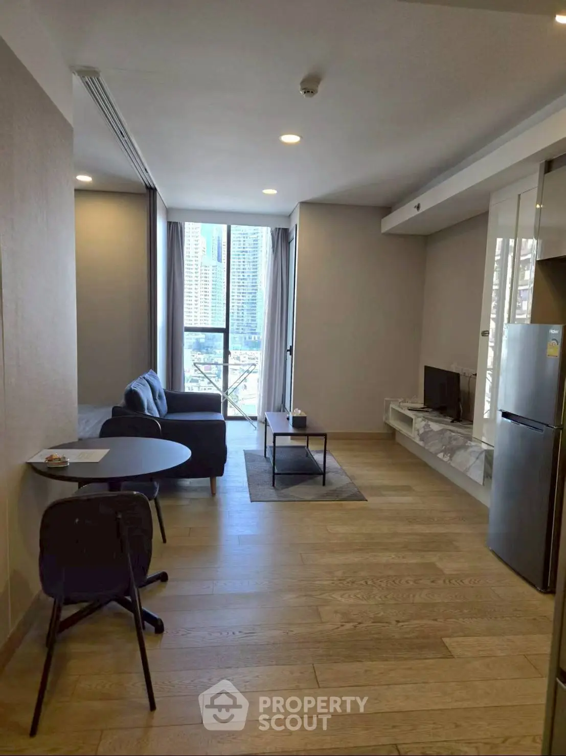 Modern living room with city view, featuring sleek furniture and wooden flooring.