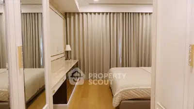 Cozy and well-lit bedroom with mirrored wardrobe doors reflecting a comfortable bed and elegant curtains, perfect for restful nights.