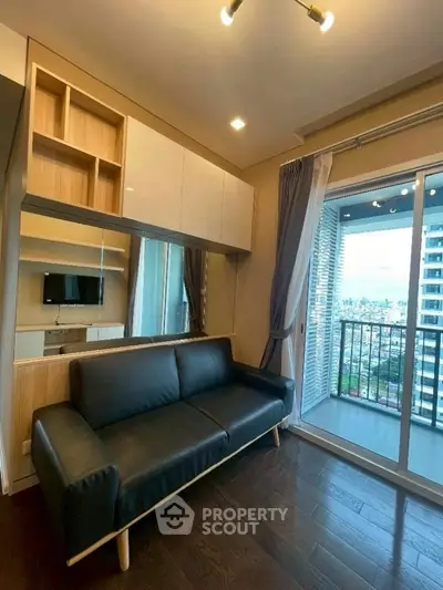 Modern living room with sleek sofa and balcony view in high-rise apartment.