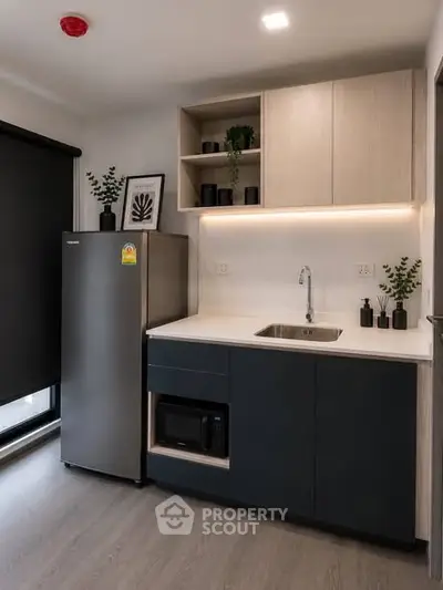 Modern kitchen with sleek cabinetry, built-in microwave, and stainless steel fridge in a stylish apartment.