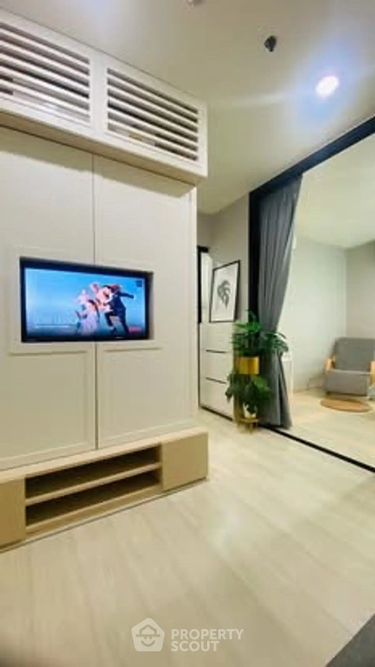 Modern living room with TV and sliding glass door leading to cozy seating area.