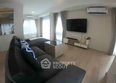 Modern living room with sleek furniture and large TV, featuring natural light and stylish decor.