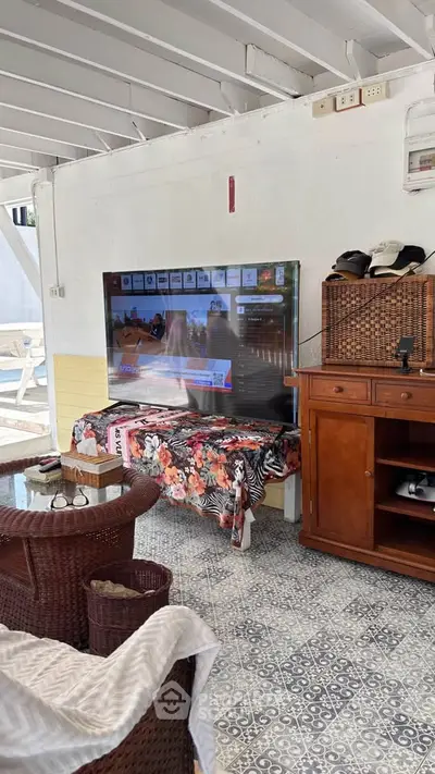 Charming outdoor living area with TV and wicker furniture, perfect for relaxation.