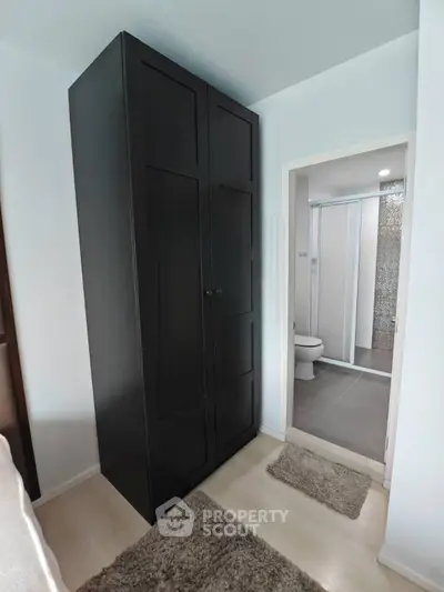 Compact bedroom with wardrobe and ensuite bathroom featuring modern shower.