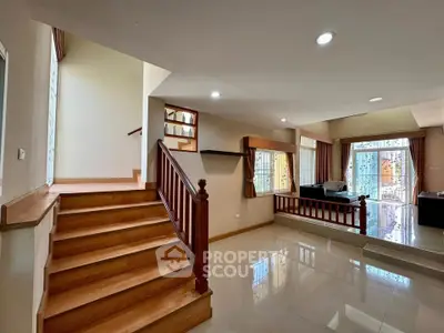 Spacious living room with elegant wooden staircase and large windows for natural light.