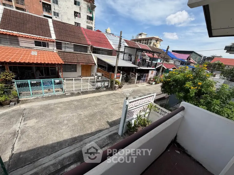 Charming urban neighborhood view from a balcony with vibrant rooftops and clear skies.