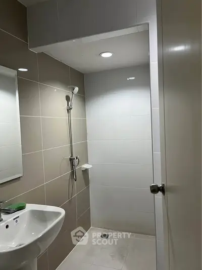 Modern bathroom with sleek tiles and shower area in contemporary apartment.