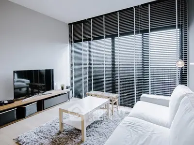 Modern living room with sleek blinds, white sofa, and flat-screen TV for stylish comfort.
