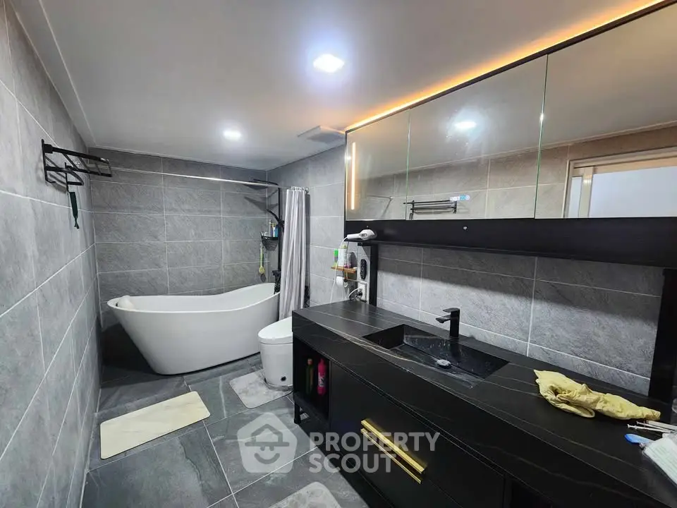Luxurious modern bathroom with sleek black vanity and elegant freestanding bathtub.