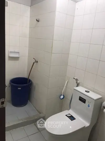 Compact bathroom with shower and toilet in a tiled setting