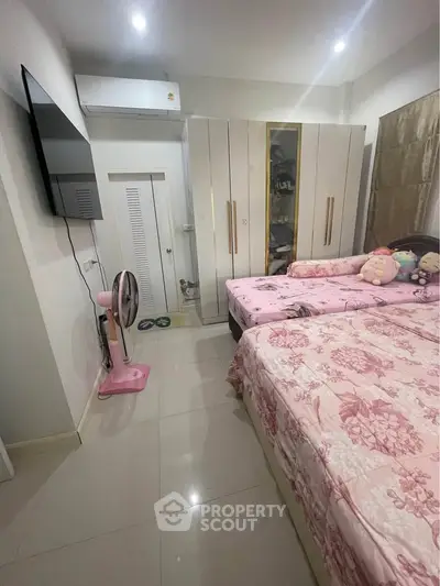 Cozy bedroom with twin beds, modern wardrobe, and wall-mounted TV in a stylish apartment.