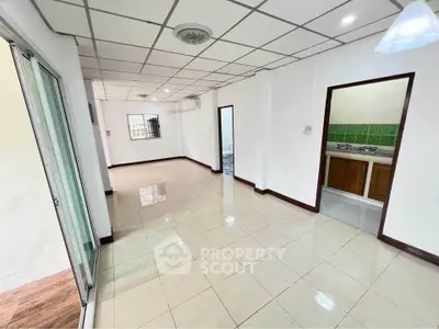 Spacious open-plan living area with tiled flooring and modern kitchen setup.