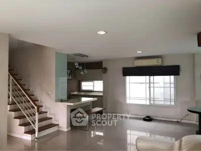 Spacious modern living area with open kitchen and staircase, featuring sleek design and ample natural light.