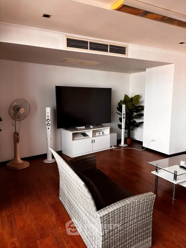 Spacious living room with modern entertainment setup and stylish wicker furniture.