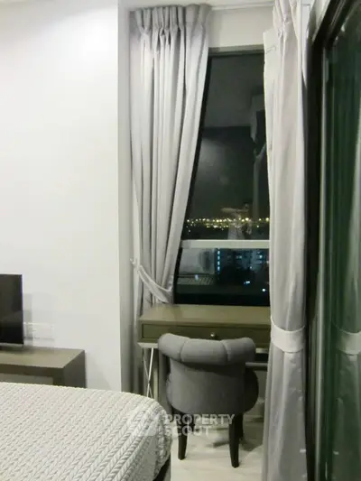 Cozy bedroom with city view, featuring elegant curtains and a stylish desk setup.