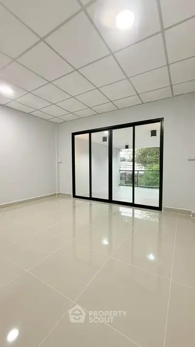 Spacious empty room with large sliding glass doors and tiled flooring, perfect for customization.