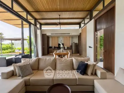 Luxurious open-plan living room with modern kitchen and pool view, featuring elegant decor and spacious seating.