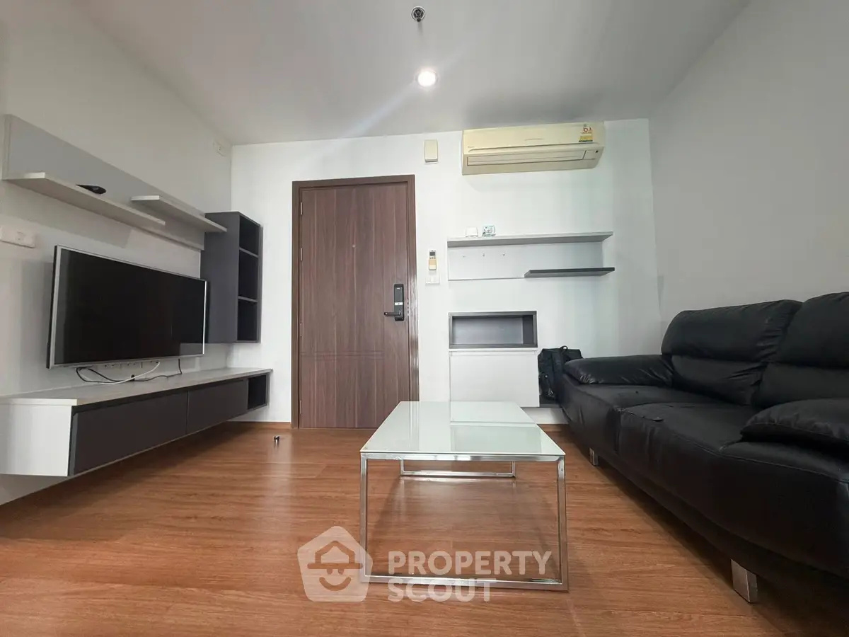 Modern living room with sleek black leather sofa and wall-mounted TV