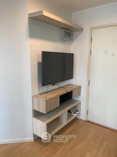 Modern living room corner with mounted TV and stylish wooden shelves in a cozy apartment.