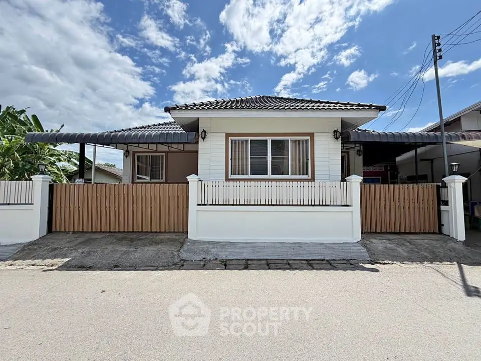 Charming single-story house with a fenced yard and tiled roof under a clear blue sky.